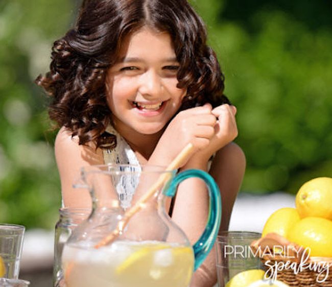 lemonade-tasting Student holding a cup with a pitcher of lemonade and some lemons as an example of fun last day of school activities
