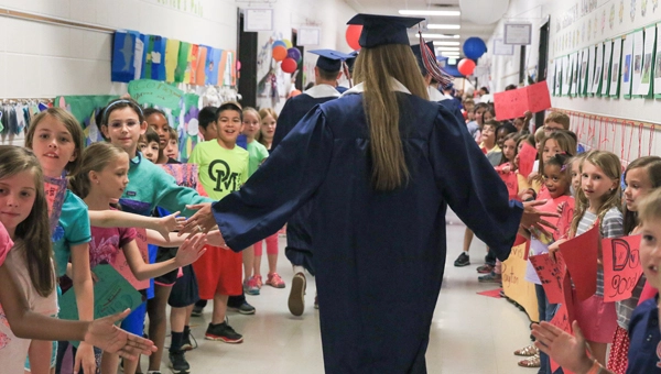 grad-walk hHgh school graduates walking through the halls of their elementary school giving students high fives