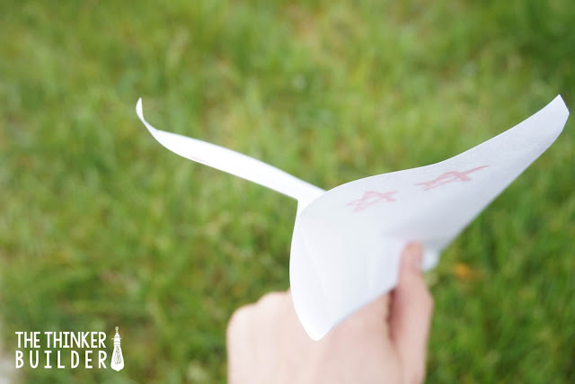 paper-airplane Child's hand holding a paper airplane with green grass in the background