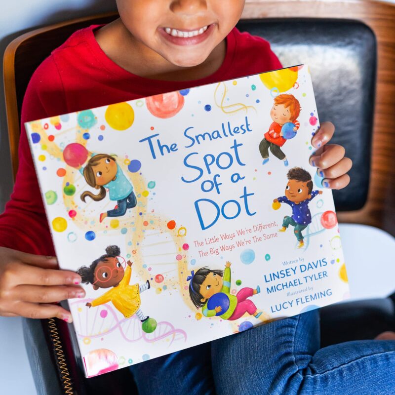 the-smallest-spot-of-a-dot Child holding one of her first day of school books entitled The Spot of a Dot