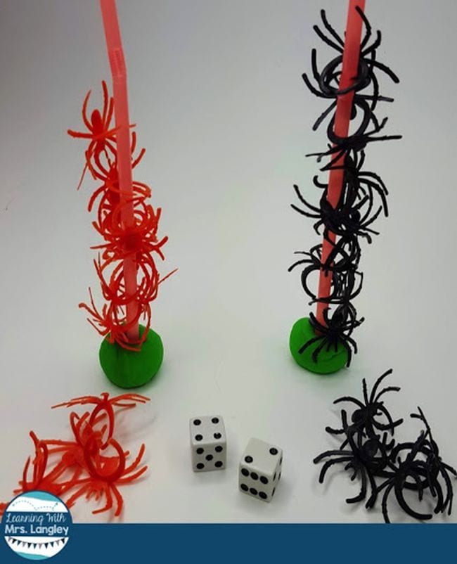 stacking-spiders Two towers, one of red plastic spiders and one of black plastic spiders and a pair of die