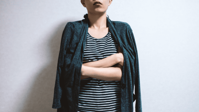 7 Signs You’re Teaching in a “Sick School” Young woman standing in front of white background in a tshirt and cardigan that is draped around her shoulders
