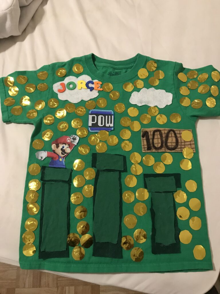 100th Day Shirt: Super Mario A green shirt features Mario from the Super Mario Brothers video game. 100 gold coins are all over the shirt.