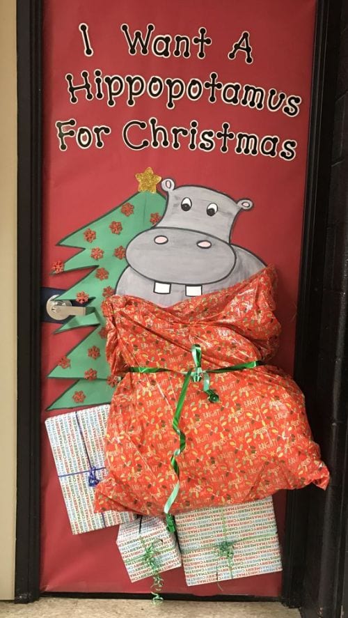 Winter Classroom Doors: Hippo Classroom door decorated with a hippo in a large bag by a Christmas tree. Text reads