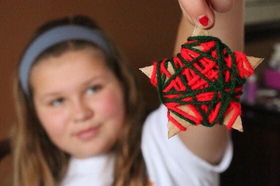 yarn-wrapped-star-ornament A little girl holds up a green and red yarn wrapped ornament