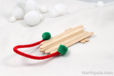 popsicle-stick-sled Five popsicle sticks glued together to form a mini sled with a pipe cleaner and pom pom handle