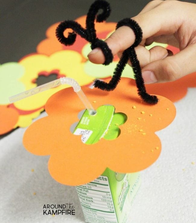 2nd Grade Science Around the Kampfire 4 Pipe cleaner twisted into bee shape on a child's finger, sitting on a paper flower