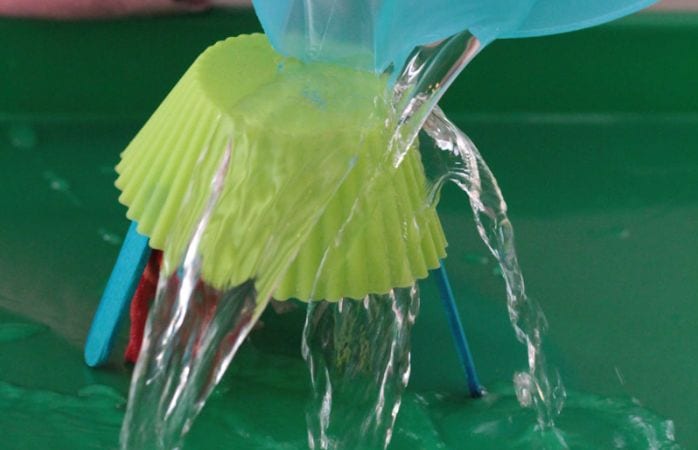 Third Grade Science Umbrellas Raising Lifelong Learners Science student pouring water over a cupcake wrapper propped on wood craft sticks