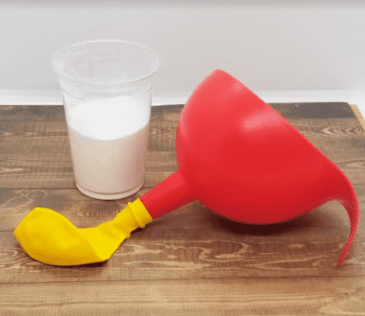 Balloon Science Experiment A plastic cup of baking soda next to a balloon attached to a funnel