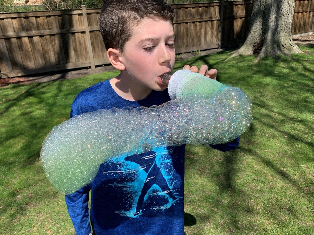 Bubble Snake Science Activity A little boy is seen blowing out a long stream of bubbles that are all attached (first grade science experiments)
