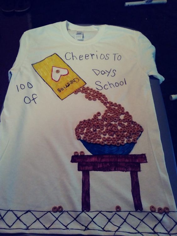100th Day Shirt: Cheerios A t-shirt says cheerios to 100 days. It has a cheerios box drawn on it, spilling real cheerios into a bowl.