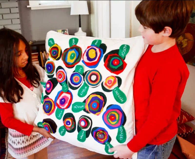 class-pillow Tow children holding a class pillow made from colorful felt circles and leaves