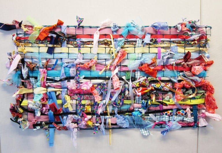 collaborative weaving A colorful wall hanging made from plastic fencing and colorful strips of cloth