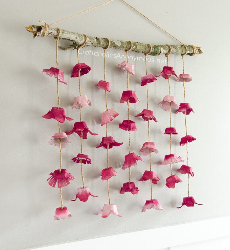 egg-carton-wall-hanging Painted sections of egg cartons hang in vertical lines from a dowel as an example of school auction art projects