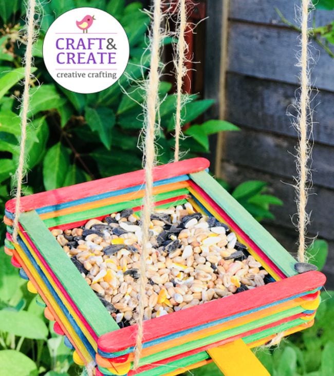 First Grade Science Projects Platform-style bird feeder built from colorful wood craft sticks and filled with mixed seed (First Grade Science Experiments)