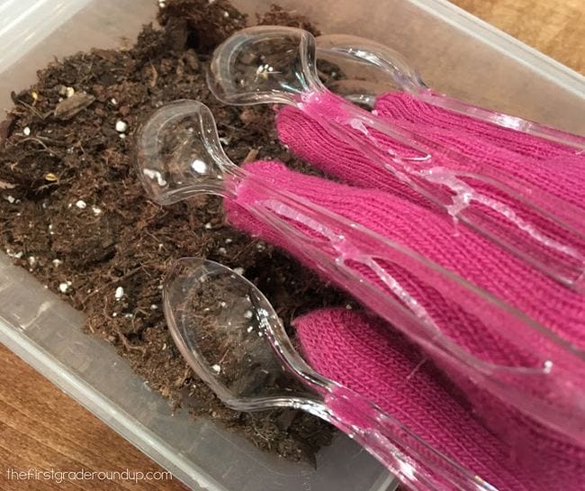 Claw Gloves Science Activity Student's hand wearing pink glove with plastic spoons attached to fingers, digging in dirt