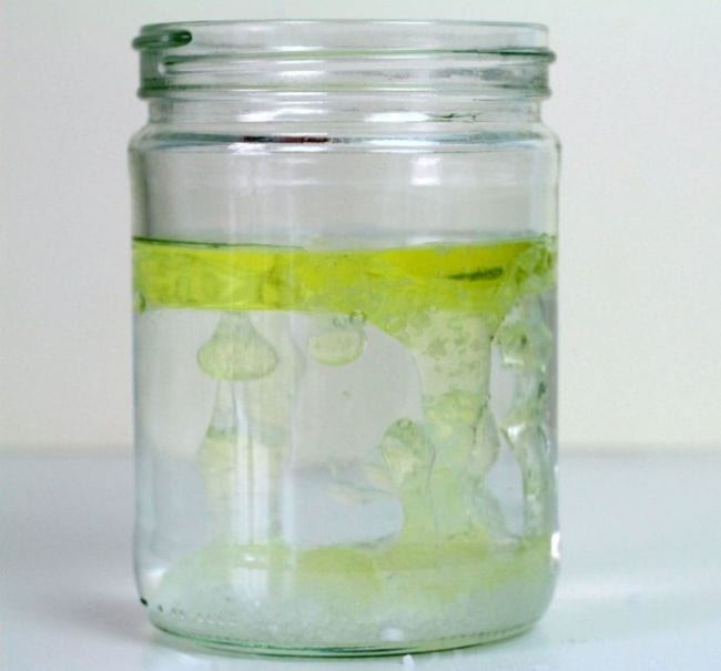 First Grade Science Experiments Glass jar filled with water and floating yellow oil