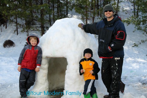 igloo family standing near an igloo that they built for a snow activity