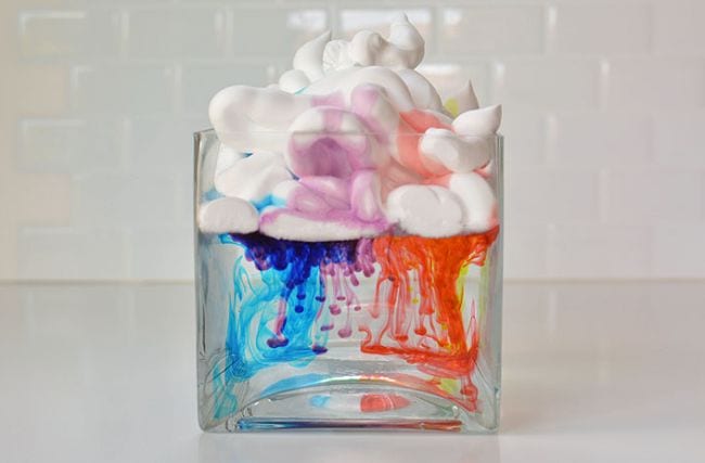 Kindergarten Science Activities Clouds Clear jar filled with water, with shaving cream floating on top and water coloring dripping from the shaving cream