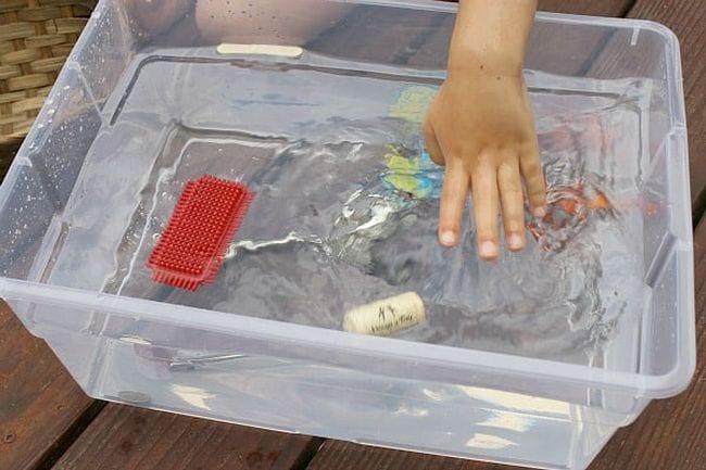Kindergarten Science Activities Sink or Float Child's hand placing items in a bin of water to see if they sink or float