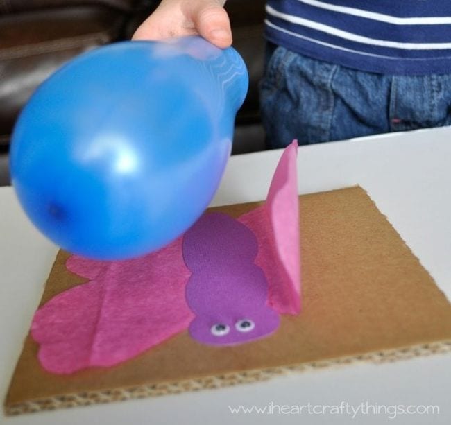 Kindergarten Science Activities Static Electricity Student's hand holding a blue balloon over a tissue paper butterfly, with wing attracted to the balloon