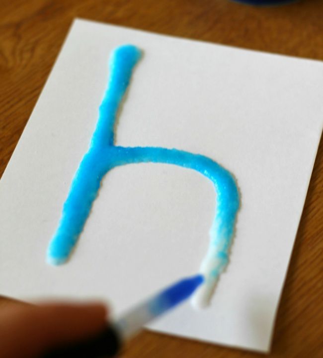 Kindergarten Science: Salt Painting Kindergarten science student using a dropper to add blue water to a lowercase H made from salt and glue