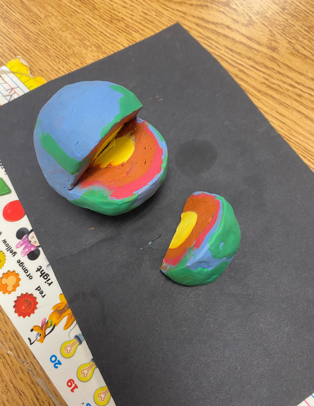 Play-Doh Earth Layers A ball of play doh has a slice taken out of it. It has a yellow center, a brown layer, a red layer, and a blue and green outer shell (first grade science experiments)
