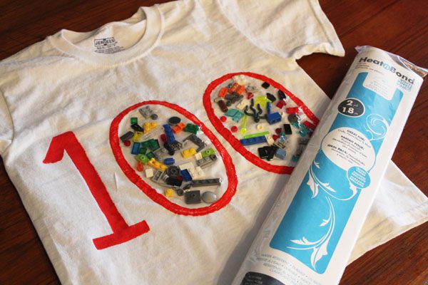 100th Day Shirt: Lego A white t-shirt has a big 100 in red on it. Inside the zeros are legos that have been glued down.