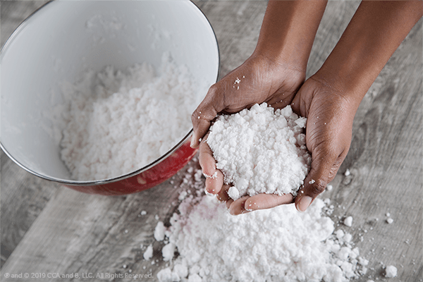 Artificial Snow Experiment A hand is shown holding fake snow from a pile.