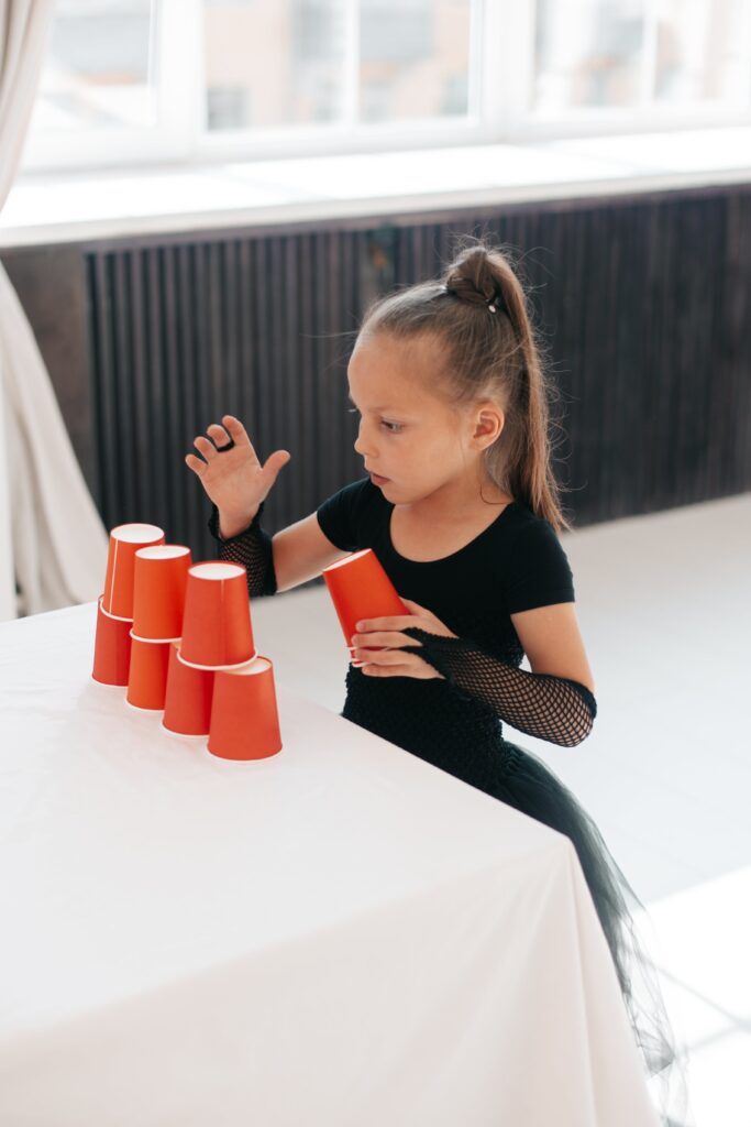 pexels-mikhail-nilov-9146910 Girl in Black Dress Stacking Paper Cups on a Table
