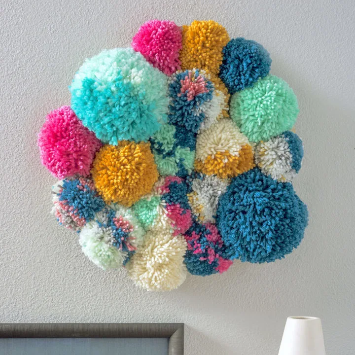 pom-pom-wall-hanging A colorful arrangement of hand made pom-poms as a wall hanging as an example of school auction art projects