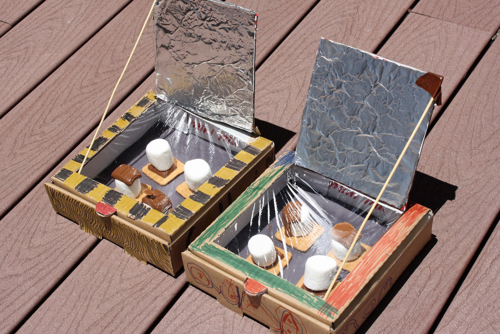 Solar Oven Smores Solar ovens made out of pizza boxes and foil with smores inside are showing a second grade science experiment relating to solar energy.