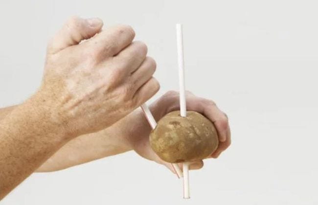 Third Grade Science Potato Straw Man's hand stabbing a sweet potato with a drinking straw