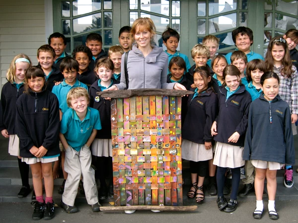 weaving A teacher and students proudly display a colorful woven painting