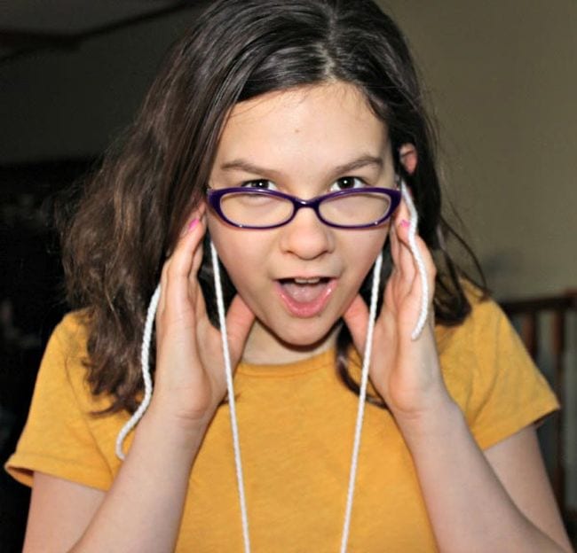 6th Grade Science Sound Waves KC Edventures Sixth grade science student holding yarn strings to her ears and looking surprised