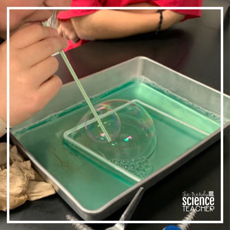 Cell Membranes Bubbles A student using a straw to blow a bubble inside another bubble in a pan of green liquid