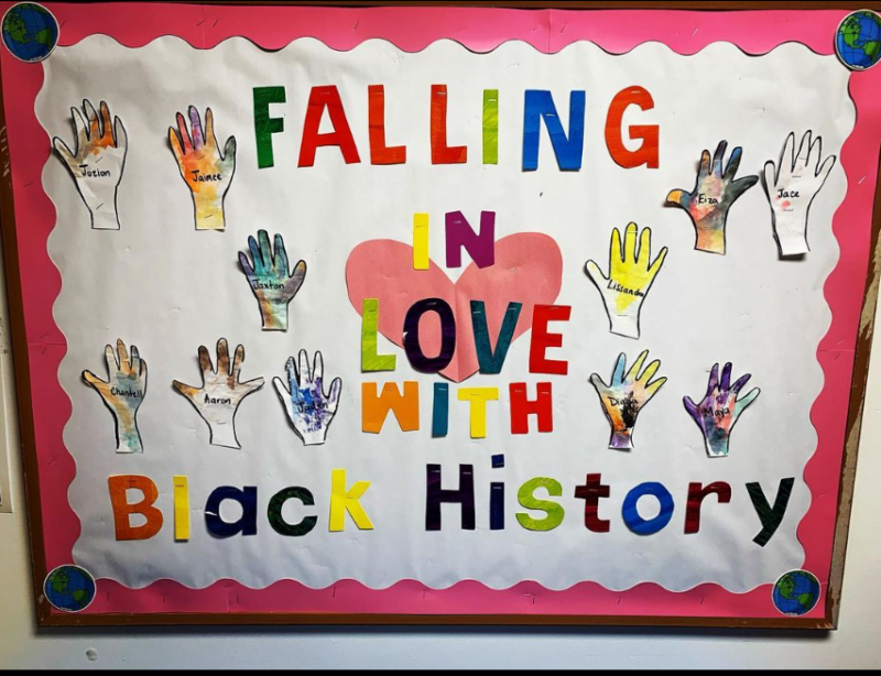 Black History Bulletin Board – Falling in Love A bulletin board says Falling in Love with Black History. It has hands with names on it and a big heart.