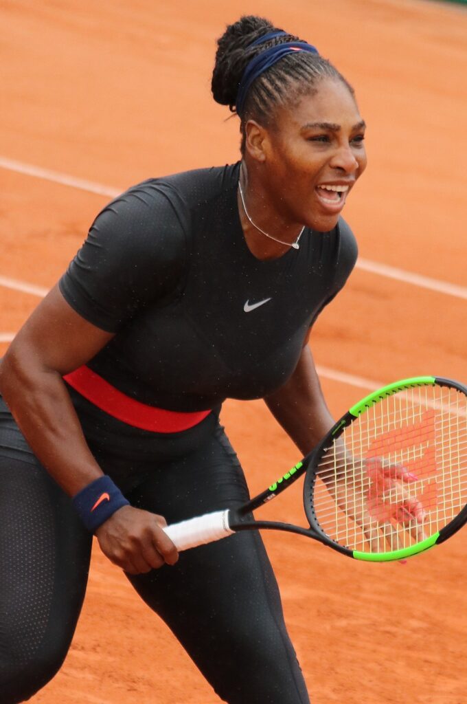 35 Famous Black Americans Everyone Should Know Serena Williams in black bodysuit with red belt on tennis court