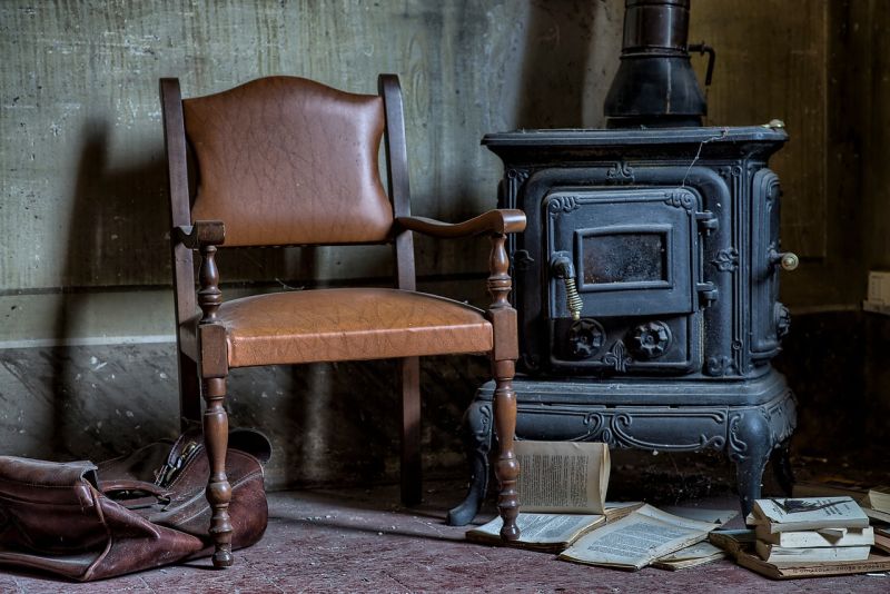 Picture Prompts: Fireside Chair A leather chair next to an old woodstove with a valise and old books
