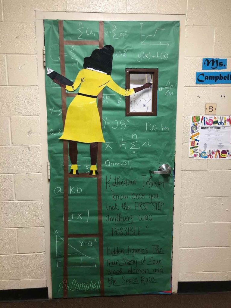 Black History Month Bulletin Board – Hidden Figures A door is decorated with a green background to look like a chalkboard. A woman is shown from behind on a ladder writing math equations on the chalkboard.