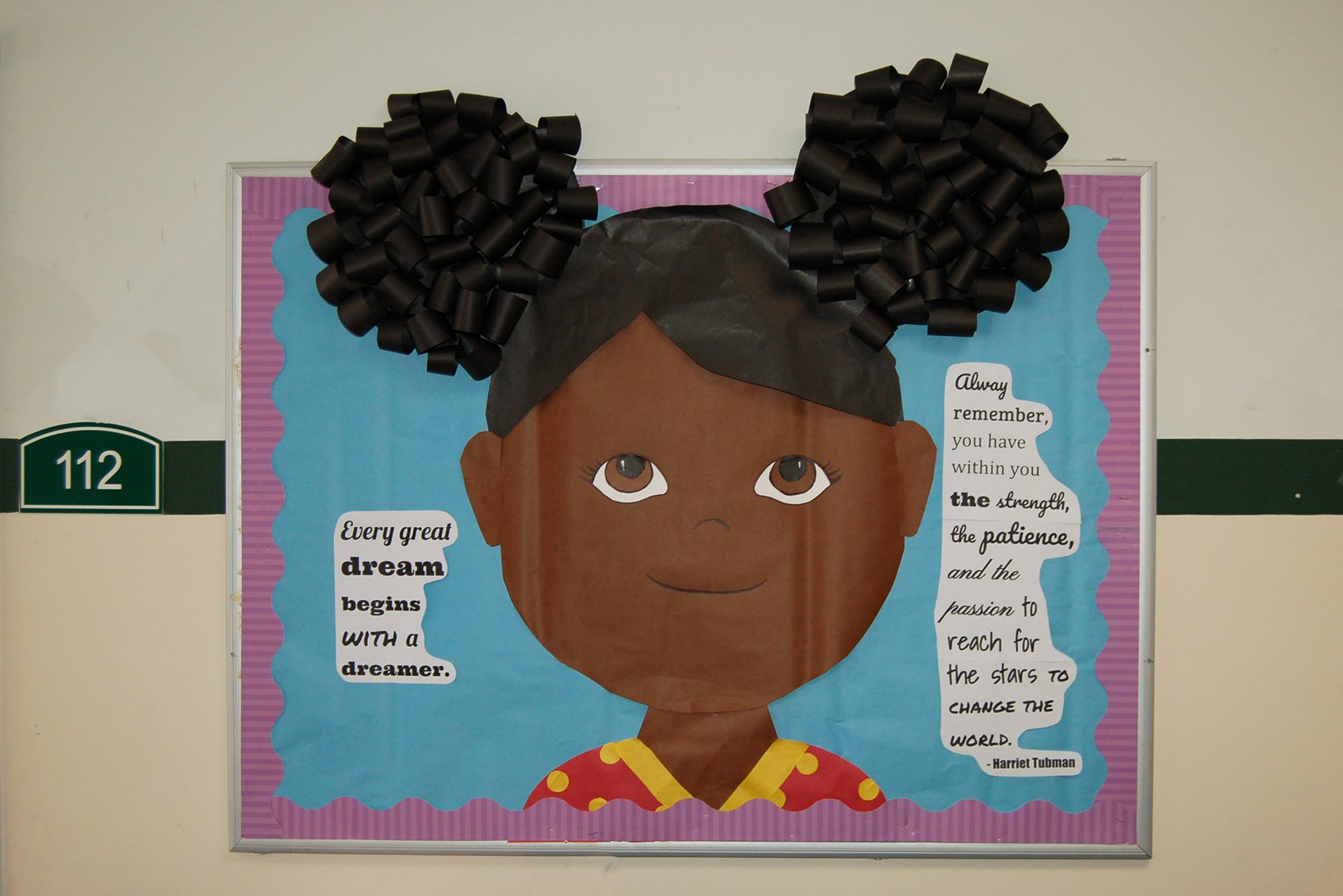 Black History Month Bulletin Board – Little Girl A bulletin board is designed to look like a little girl from the shoulders up. It has a quote by Harriet Tubman to the right of the girl.