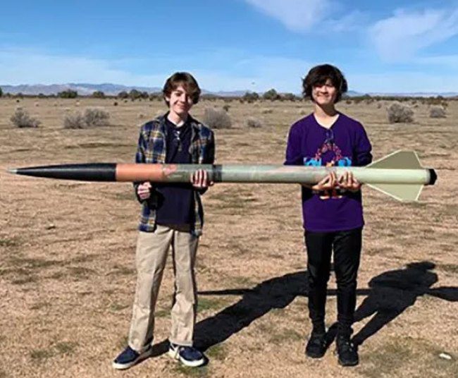 Project Based Learning Ideas: Rocket Two students holding a large model rocket built as part of project based learning