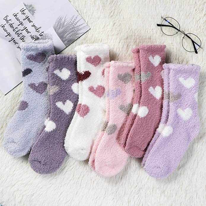 Heart Socks Six pairs of fuzzy heart socks with a note and glasses on a rug, as an example of teacher valentine gift.