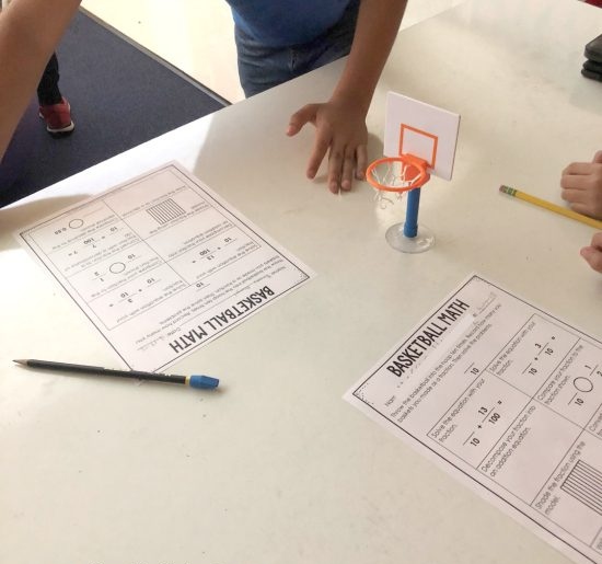 basketball-fractions Desktop with a tiny basketball hoop, fraction worksheets, a pencil and a student's hand