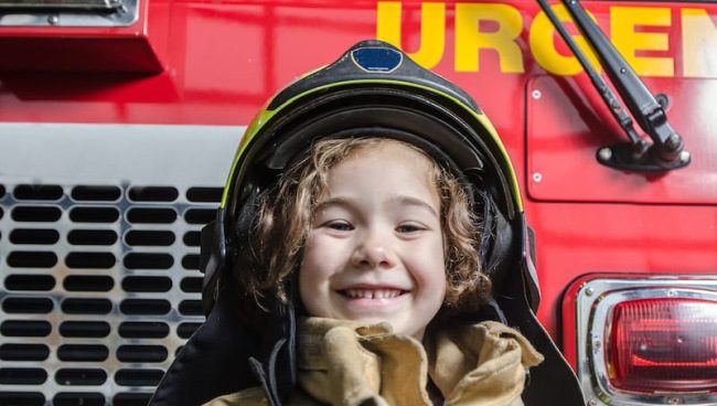 Field Trip Ideas: PreK Preschooler wearing a fire helmet and standing in front of a fire truck (Field Trip Ideas)