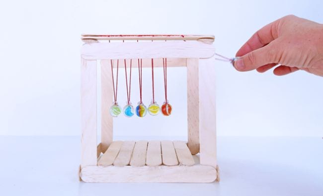 8th Grade Science Babble Dabble Do Newton's Cradle built of wood craft sticks, yarn, and marbles