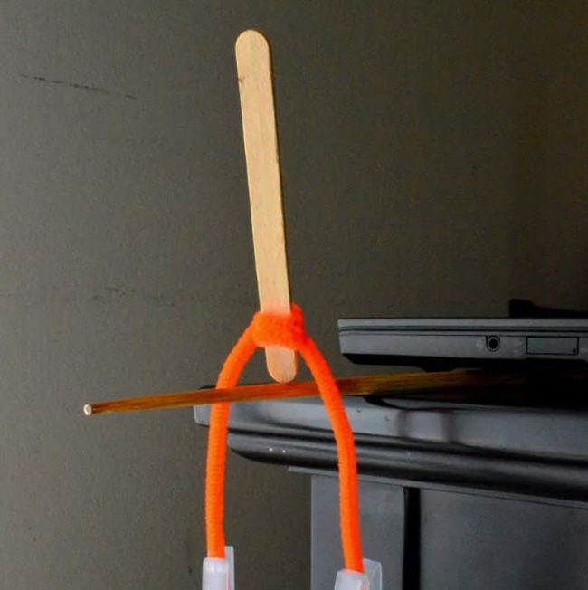 8th Grade Science Rookie Parenting Wood craft stick balanced on end on a pencil, with orange pipe cleaner twisted around it