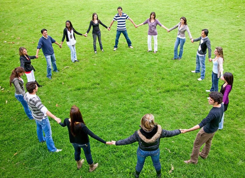 Circle-Games Teens standing in a circle on the grass, holding hands as an example of Pi Day activities