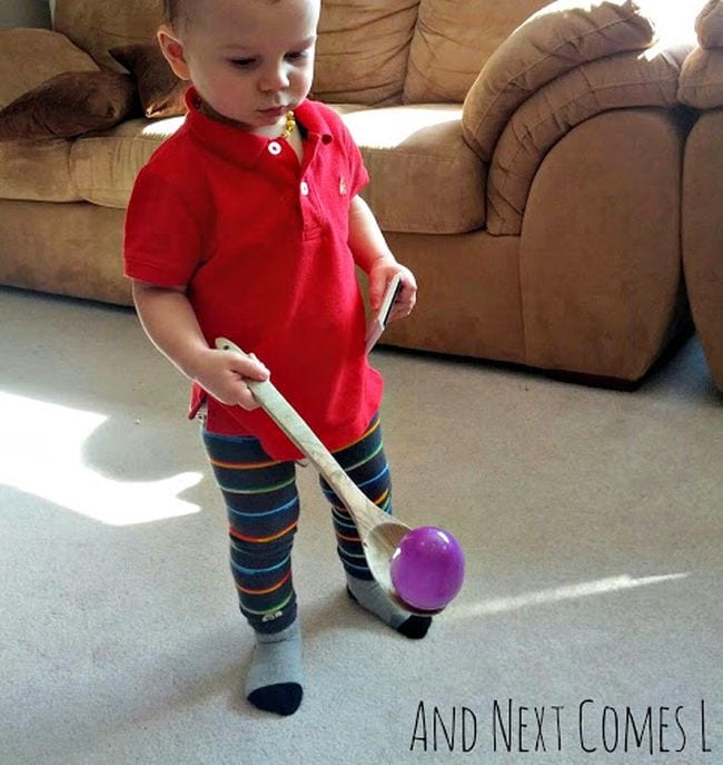 Easter Egg Activities And Next Comes L Toddler carrying a plastic egg on a wooden spoon