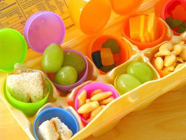 Easter Egg Activities Gluesticks Plastic eggs filled with small snacks like grapes and goldfish crackers, set into a foam egg crate (Easter Egg Activities)